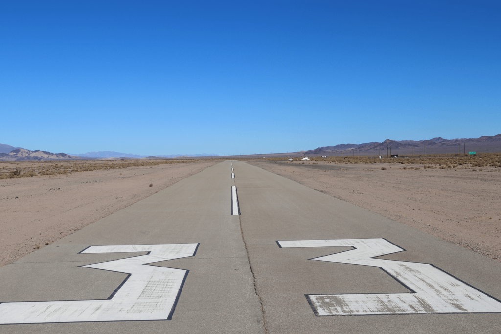 An airport runway with the number 33 spray painted in white with desert landscape and mountains shown on the left and right sides.