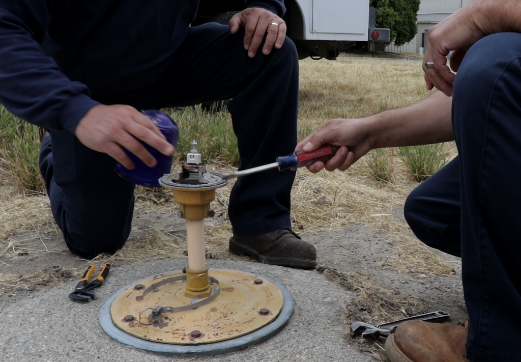 Two airport maintenance men work on repairing an airport runway light.