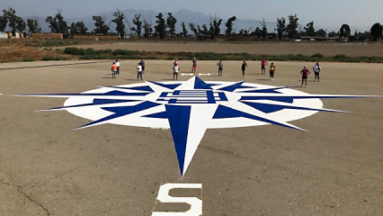 A group pf women pilot stand o the Chino Airport runway in front of a recently painted navigation compass in white and blue for pilots to use as navigation from the air.