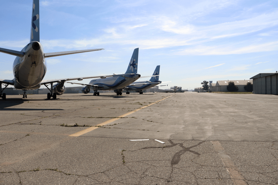 A row of three jets are parked on the taxiway at Chino Airport.
