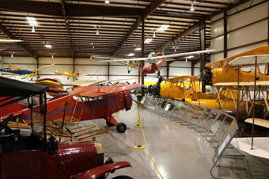An inside view of Yanks vintage hangar where vintage airplanes are on display, including a vintage early 20th Century automobile. 
