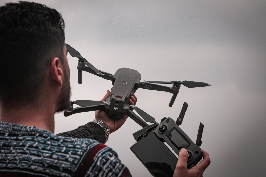 A close up of a man with a beard side view holding a DJI drone in his hand.