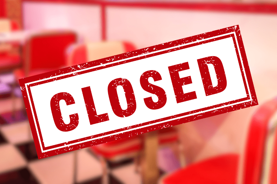 Closed sign with diner booth in background.
